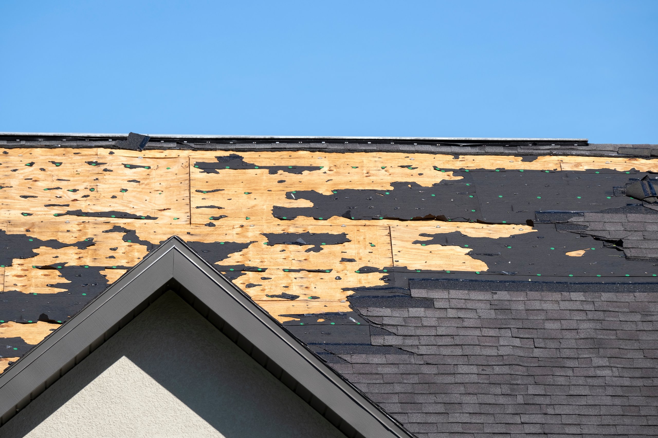 Damaged roof with missing shingles after storm