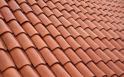 Clean new terracotta clay roof tiles with curved profile in neat overlapping rows